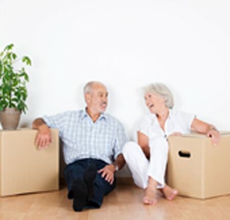 Elderly person moving into a nursing home with caregiver carrying boxes UK